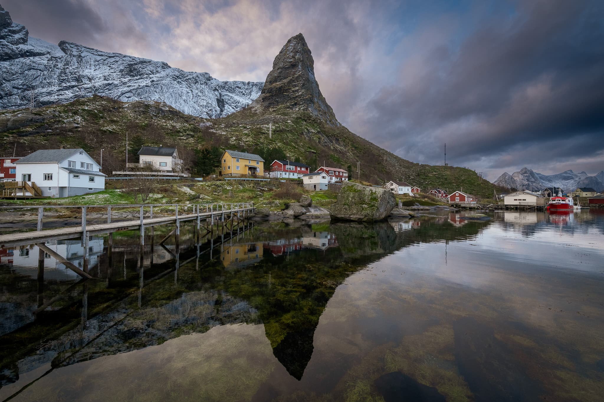 A Norwegian fishing village beneath a dramatic mountain and reflected in still water, photographed by Mohammad Anabtawi